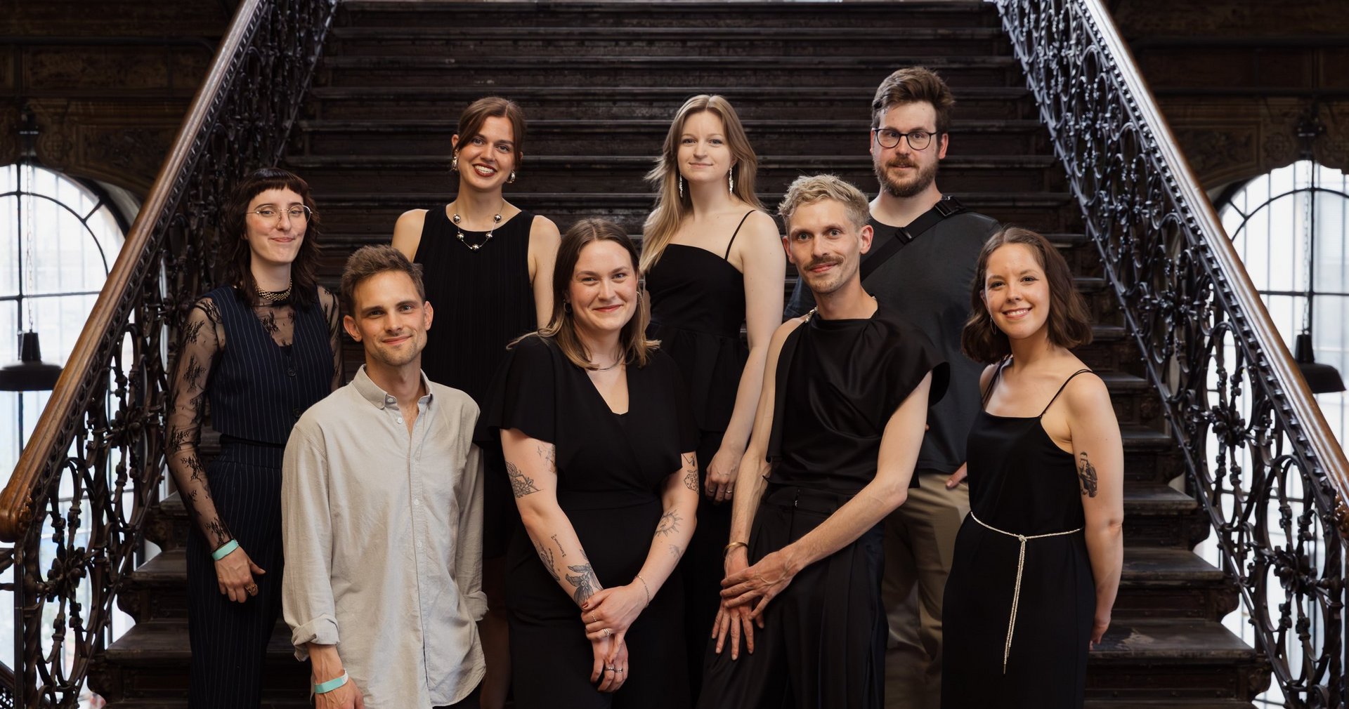 kreHtiv Teamfoto im Treppenhaus der Cumberlanfdschen. Alle tragen schwarz und lachen in die Kamera.