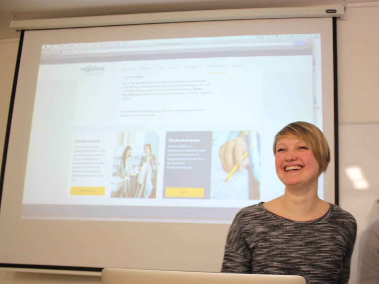 Bild von Chrissi, die etwas präsentiert und herzlich lacht.