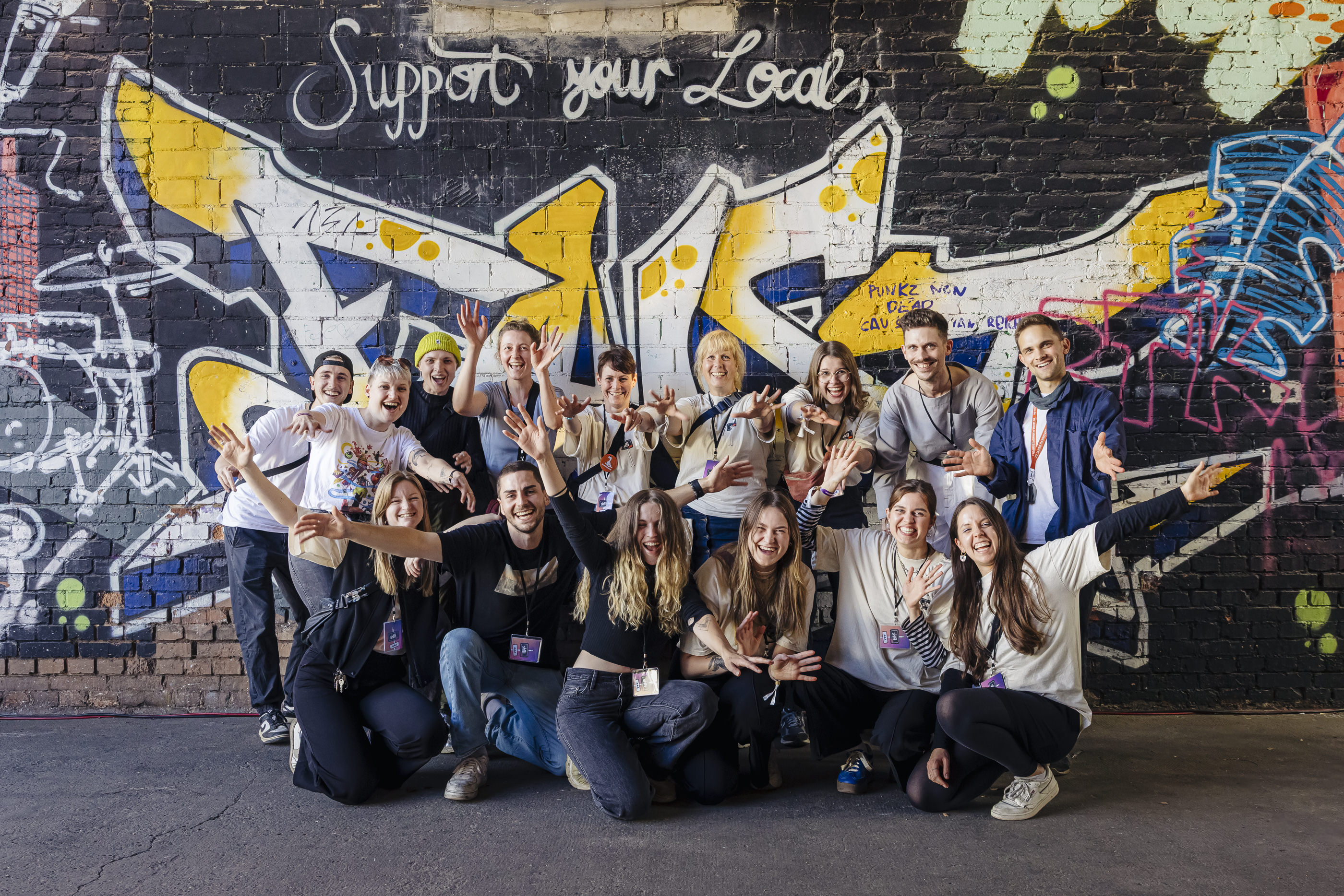 Man sieht das SHIFT NOW Projektteam auf einem Gruppenbild. Alle strecken die Arme aus und freuen sich.