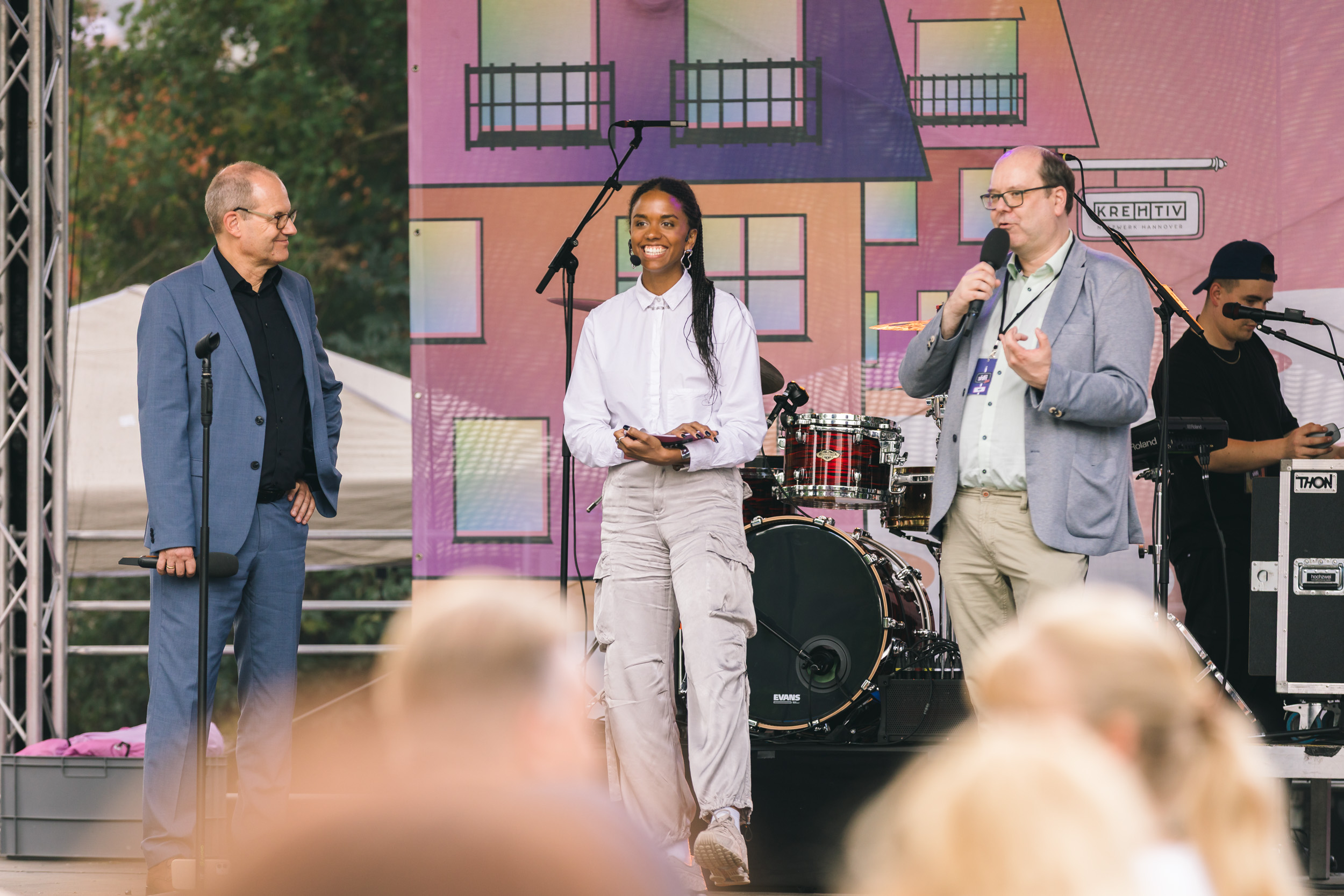 Der niedersächsische Umweltminister Christian Meyer und Wirtschaftsdezernent der REGION HANNOVER Ulf-Birger Franz zusammen mit Moderatorin Diona Bathily auf der SHIFT NOW Bühne.