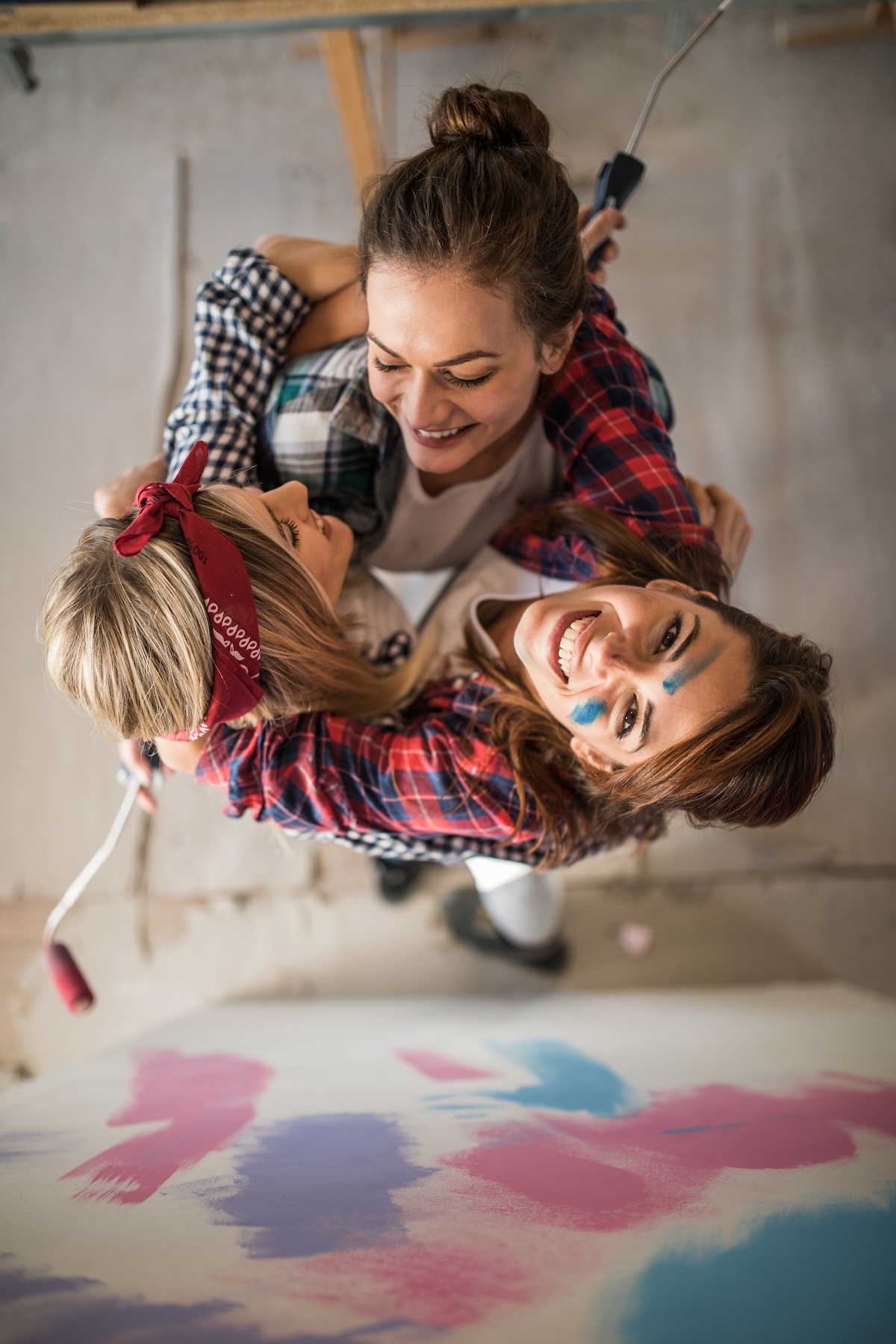 Drei Frauen halten sich fest im Arm halten und haben Streichutensilien in der Hand.
