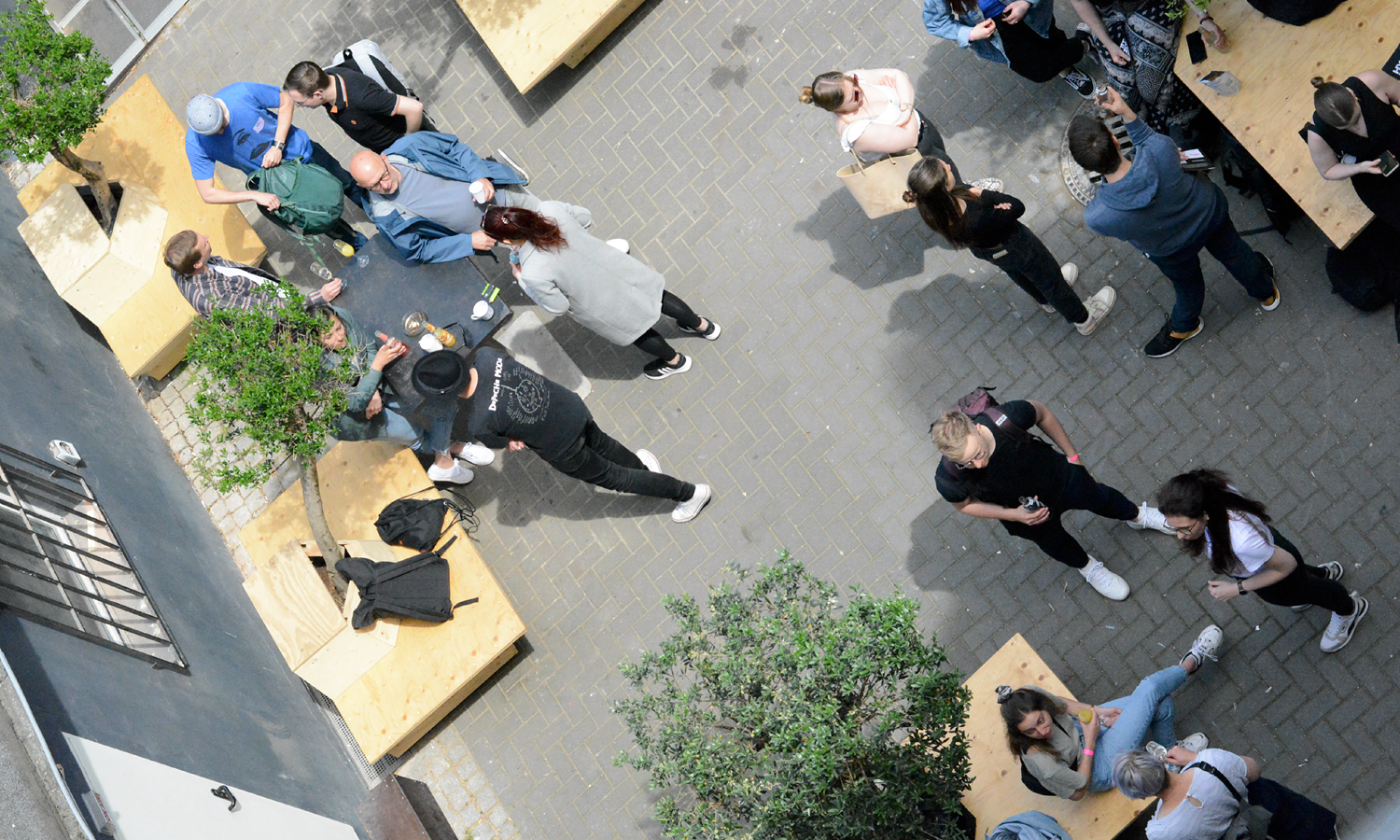 Menschen in einem Innenhof im Sommer, die sich unterhalten und in der Sonne sitzen.